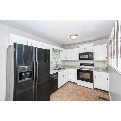 A kitchen with black appliances and white cabinets.
