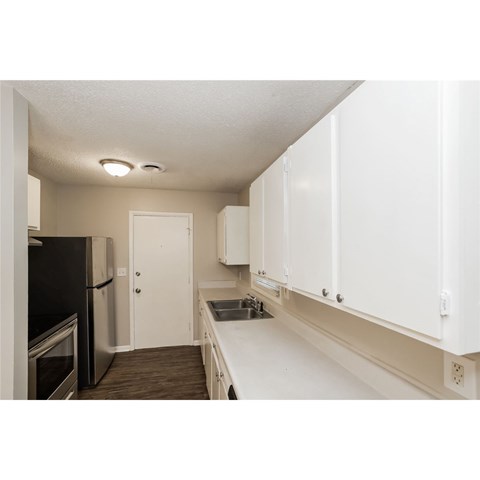 A kitchen with white cabinets and a black fridge.