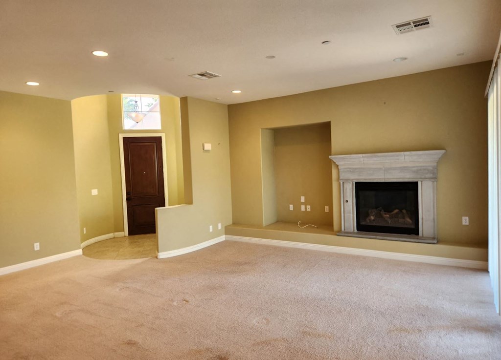 a empty living room with a fireplace and a door