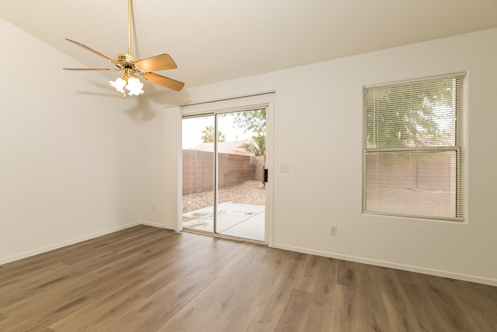 A room with a ceiling fan and sliding glass doors.