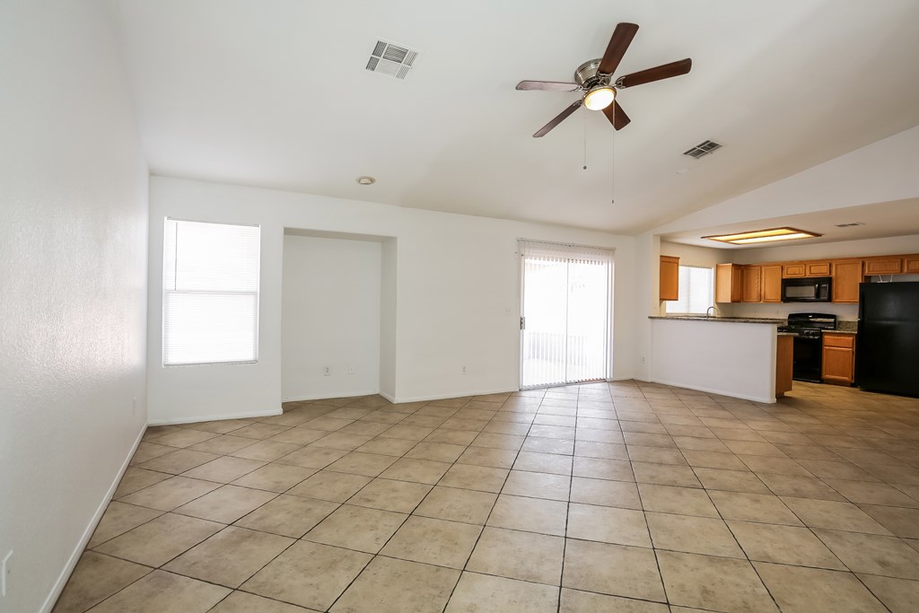 A spacious living room with a ceiling fan and tiled flooring.