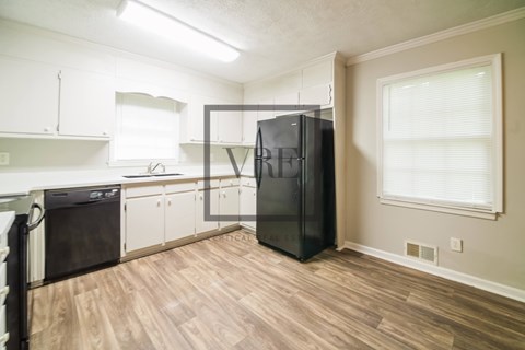 A kitchen with a black fridge and wooden floors.