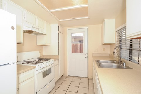 A kitchen with white appliances and a white door.