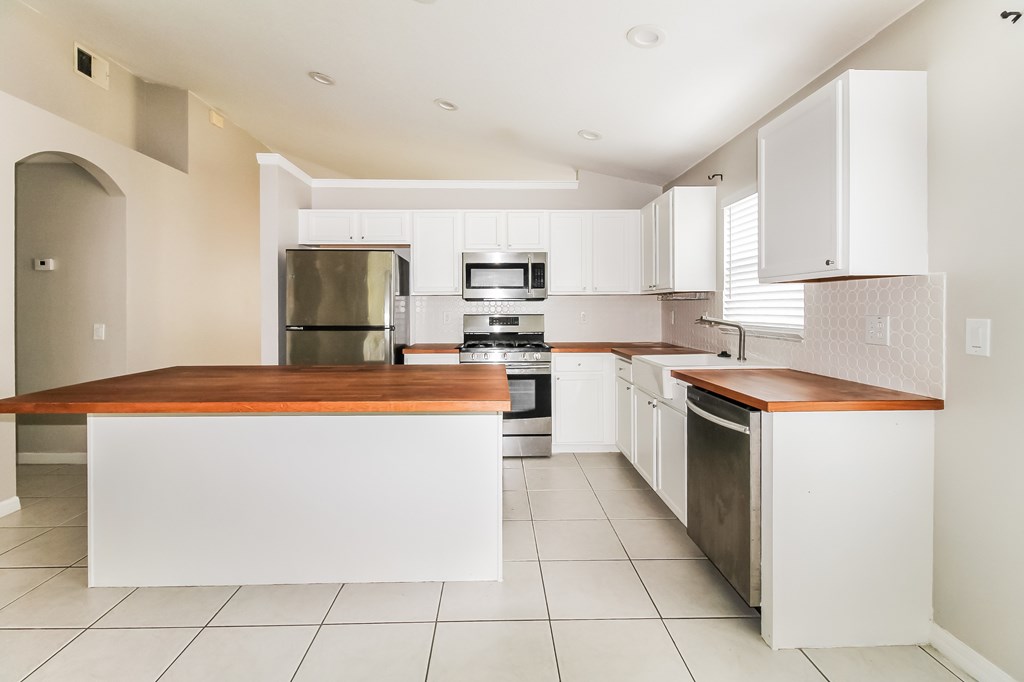 A kitchen with white cabinets and a wooden island.