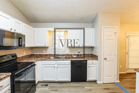 A kitchen with white cabinets and black appliances.