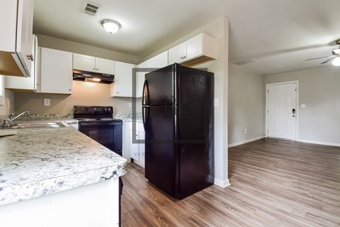 A kitchen with a black fridge and a marble counter top.
