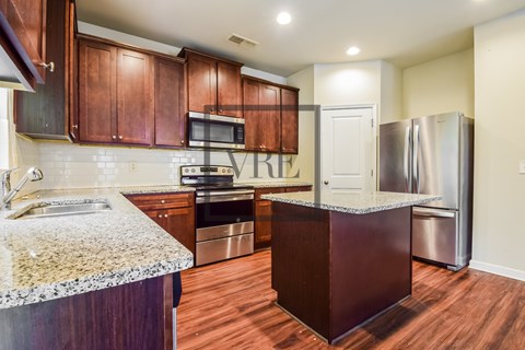 A kitchen with brown cabinets and a granite counter top.