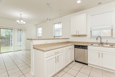 A kitchen with white cabinets and a granite countertop.