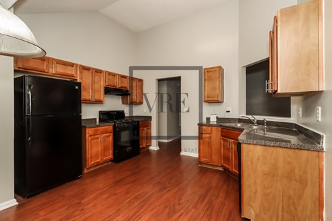 A kitchen with wooden cabinets and a black refrigerator.