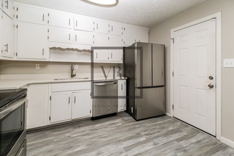 A kitchen with a refrigerator, oven, and microwave.