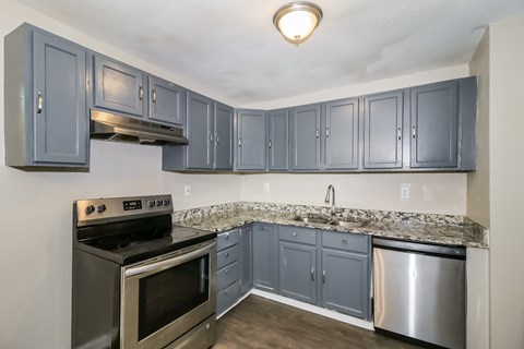 A kitchen with a stove, oven, and cabinets.