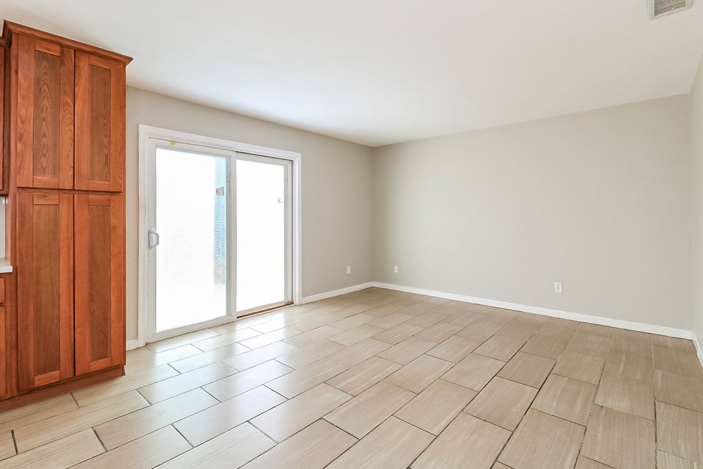 A room with wooden flooring and a wooden cabinet with a white door.