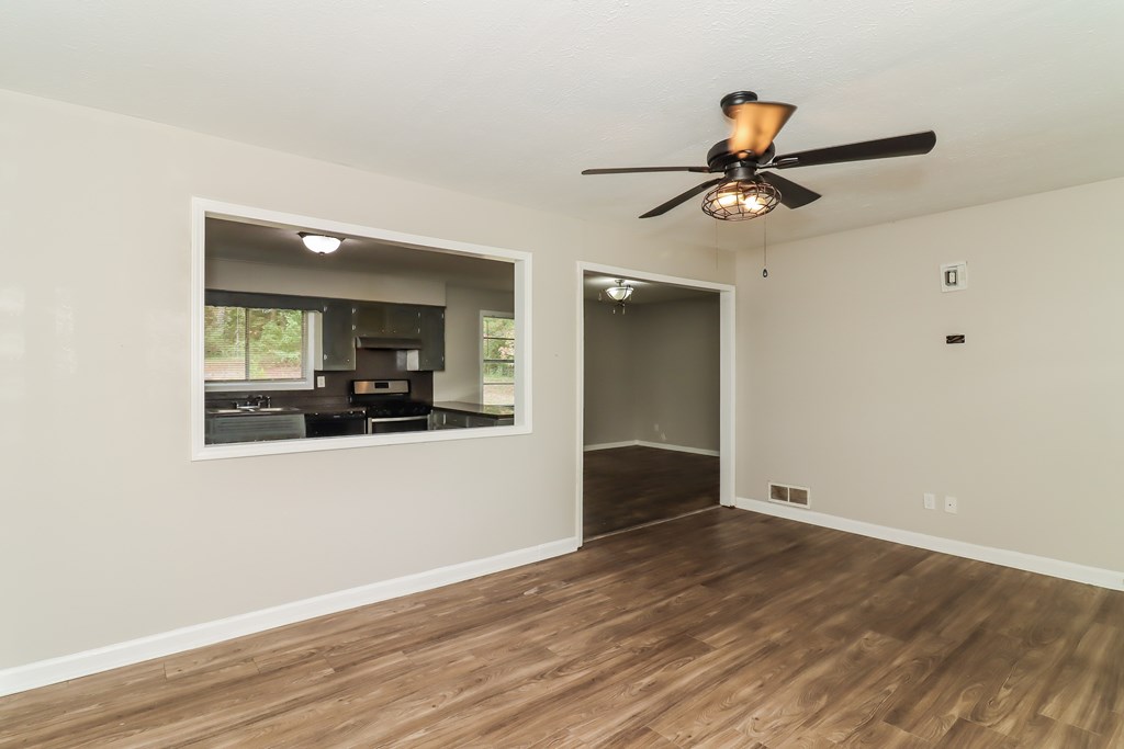 A room with a ceiling fan and wooden flooring.