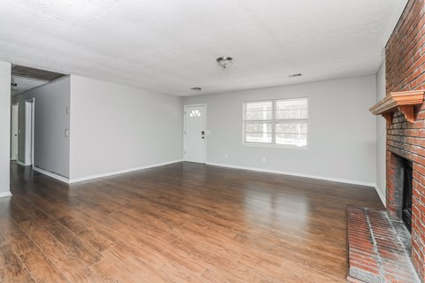 A room with wooden floors and a brick fireplace.