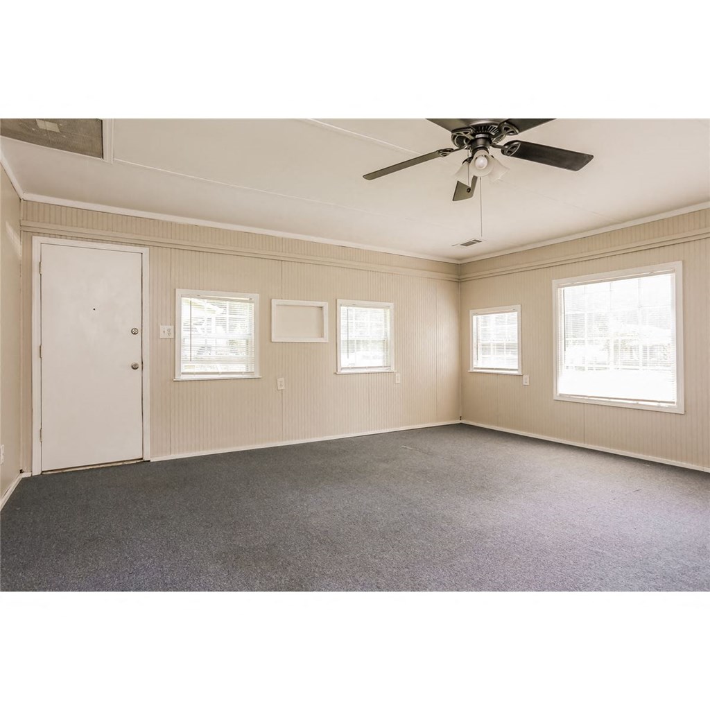an empty living room with a ceiling fan