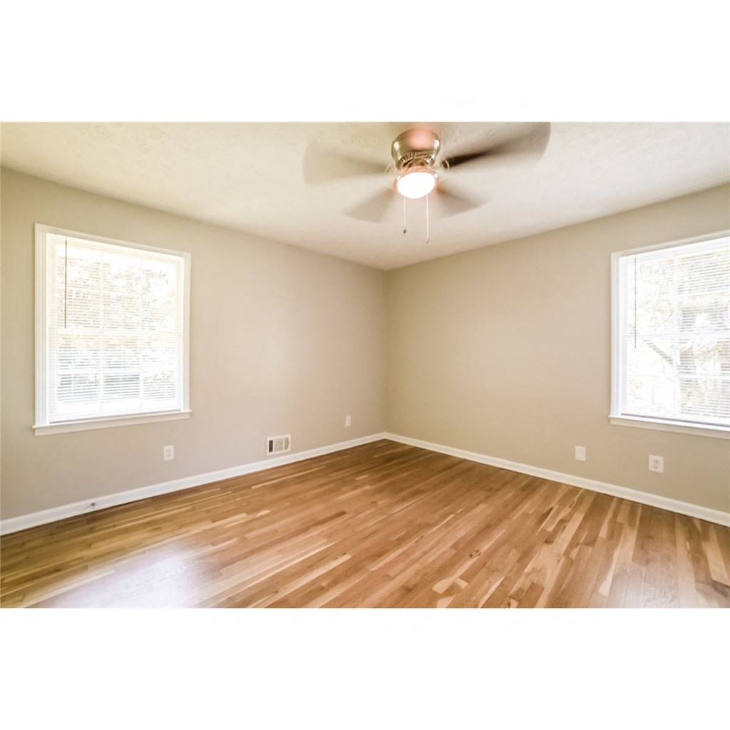 an empty living room with wood floors and a ceiling fan