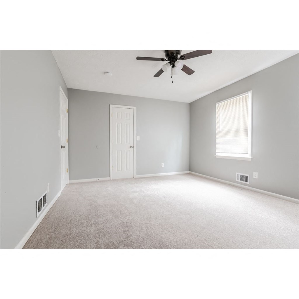 an empty living room with a ceiling fan