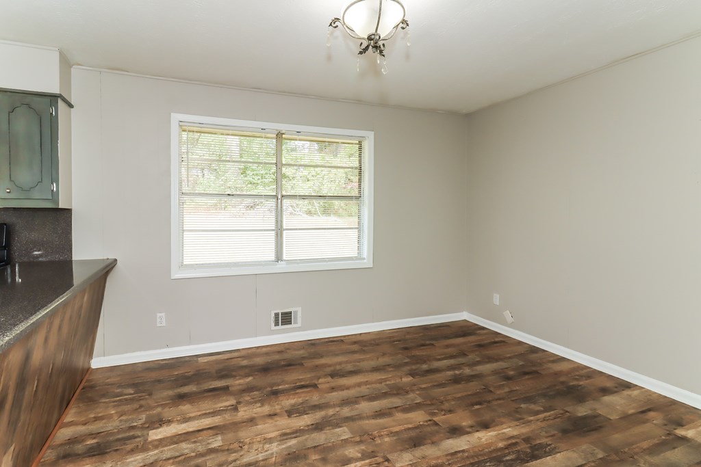 A room with wooden flooring and a window with blinds.