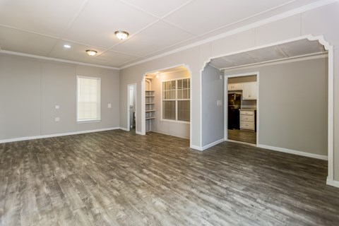A spacious room with wood flooring and white walls.