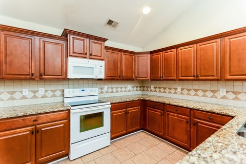 A kitchen with brown cabinets and a white stove top oven.