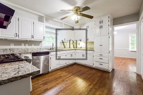A kitchen with white cabinets and a marble countertop.