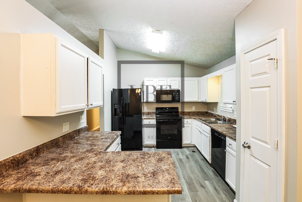 A kitchen with granite countertops and white cabinets.