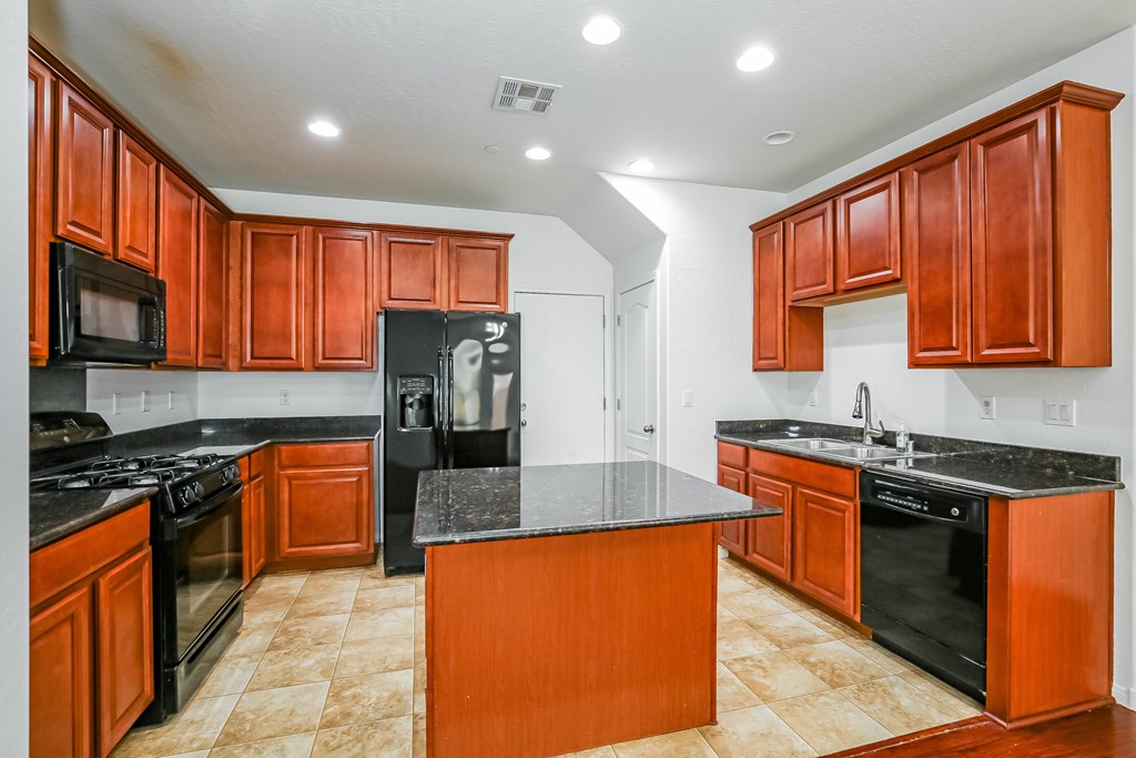 A kitchen with brown cabinets and black appliances.