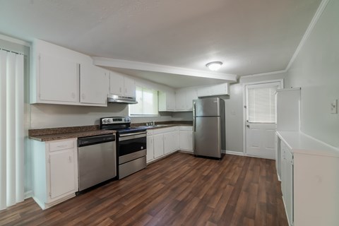 A kitchen with white cabinets and a wooden floor.