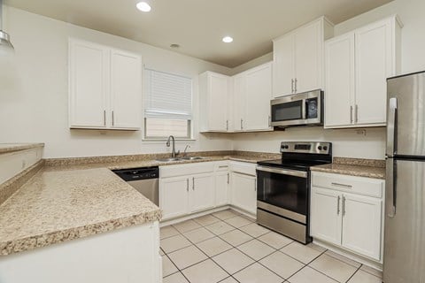 A kitchen with white cabinets and appliances.