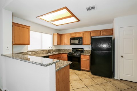 A kitchen with black appliances and wooden cabinets.