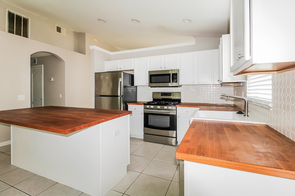 A modern kitchen with a wooden countertop and stainless steel appliances.
