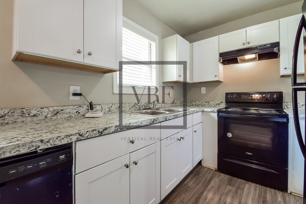 A modern kitchen with white cabinets and a black oven.