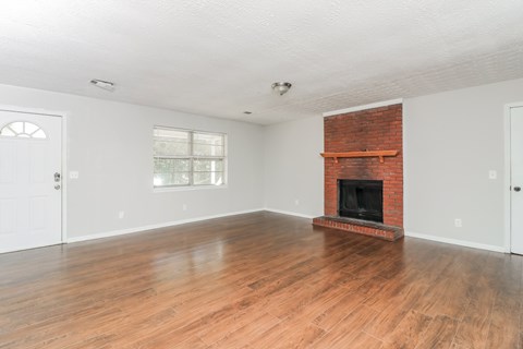 A room with a fireplace and wooden floors.