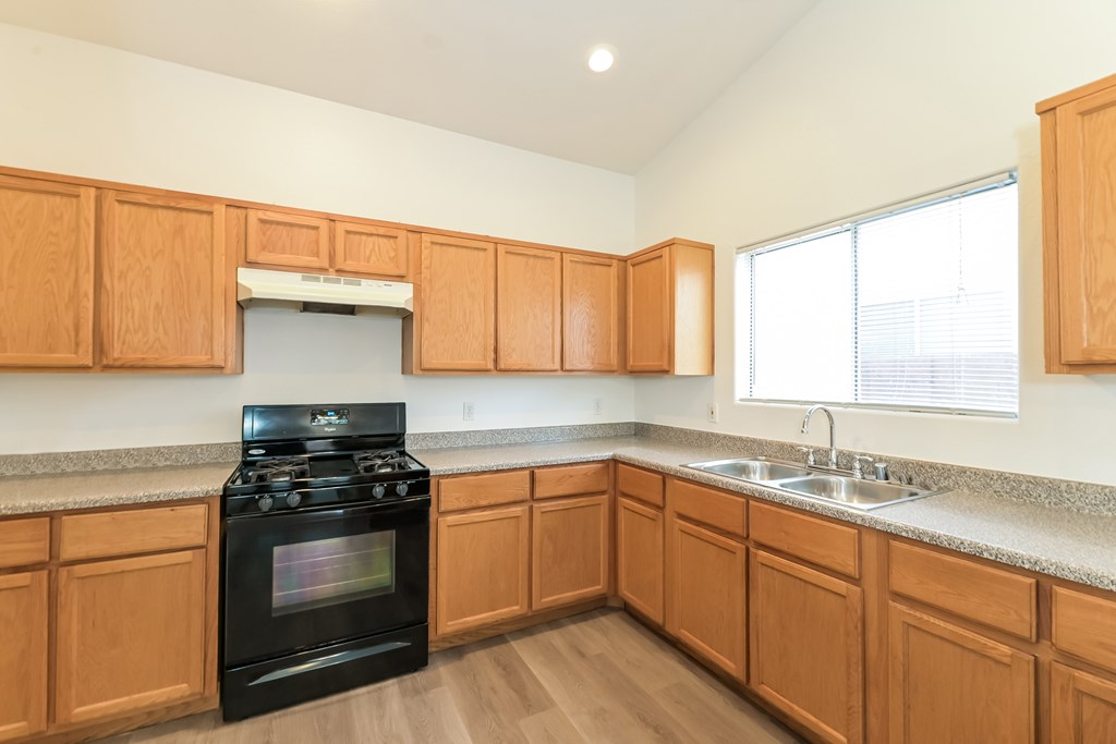 A kitchen with wooden cabinets and a black stove top oven.