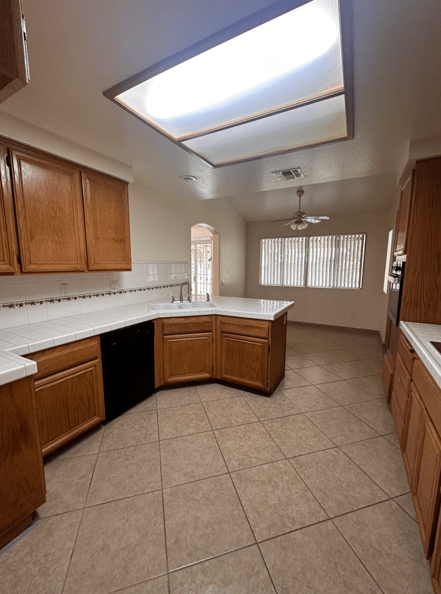 an empty kitchen with a skylight and wooden cabinets