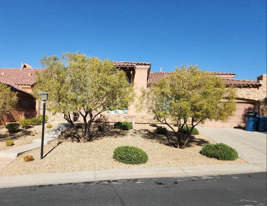 a yard with trees and bushes in front of a house
