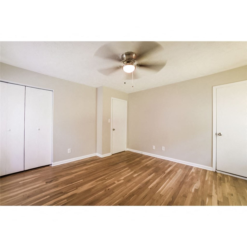 an empty living room with a ceiling fan