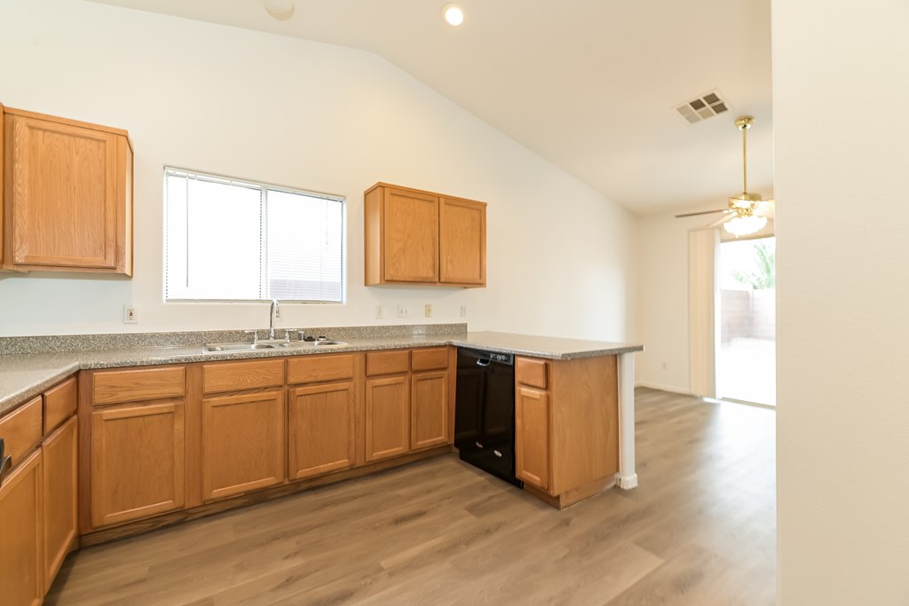 A kitchen with wooden cabinets and a black dishwasher.