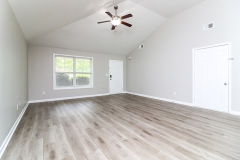 A room with a ceiling fan and a window with blinds.