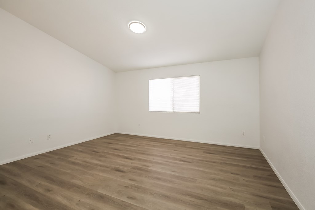 A room with wooden flooring and a window letting in natural light.