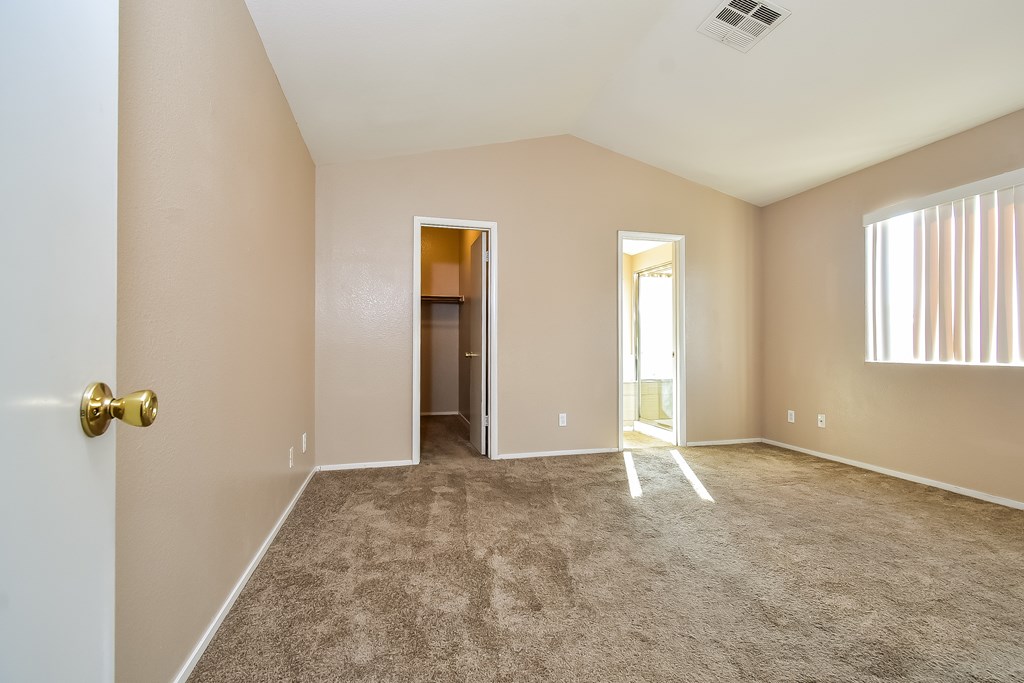 A room with a carpeted floor and a doorway leading to another room.