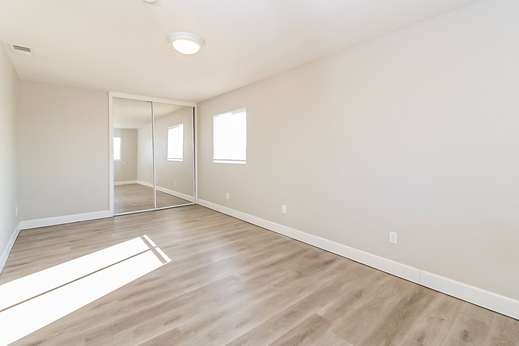 A room with wooden flooring and a large mirror on the wall.