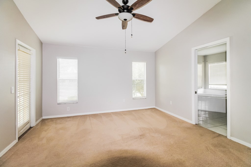 A room with a ceiling fan and carpeted floor.
