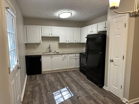 a kitchen with white cabinets and a black refrigerator