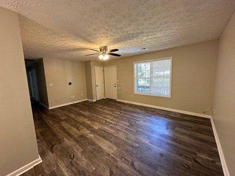 an empty living room with wood floors and a ceiling fan