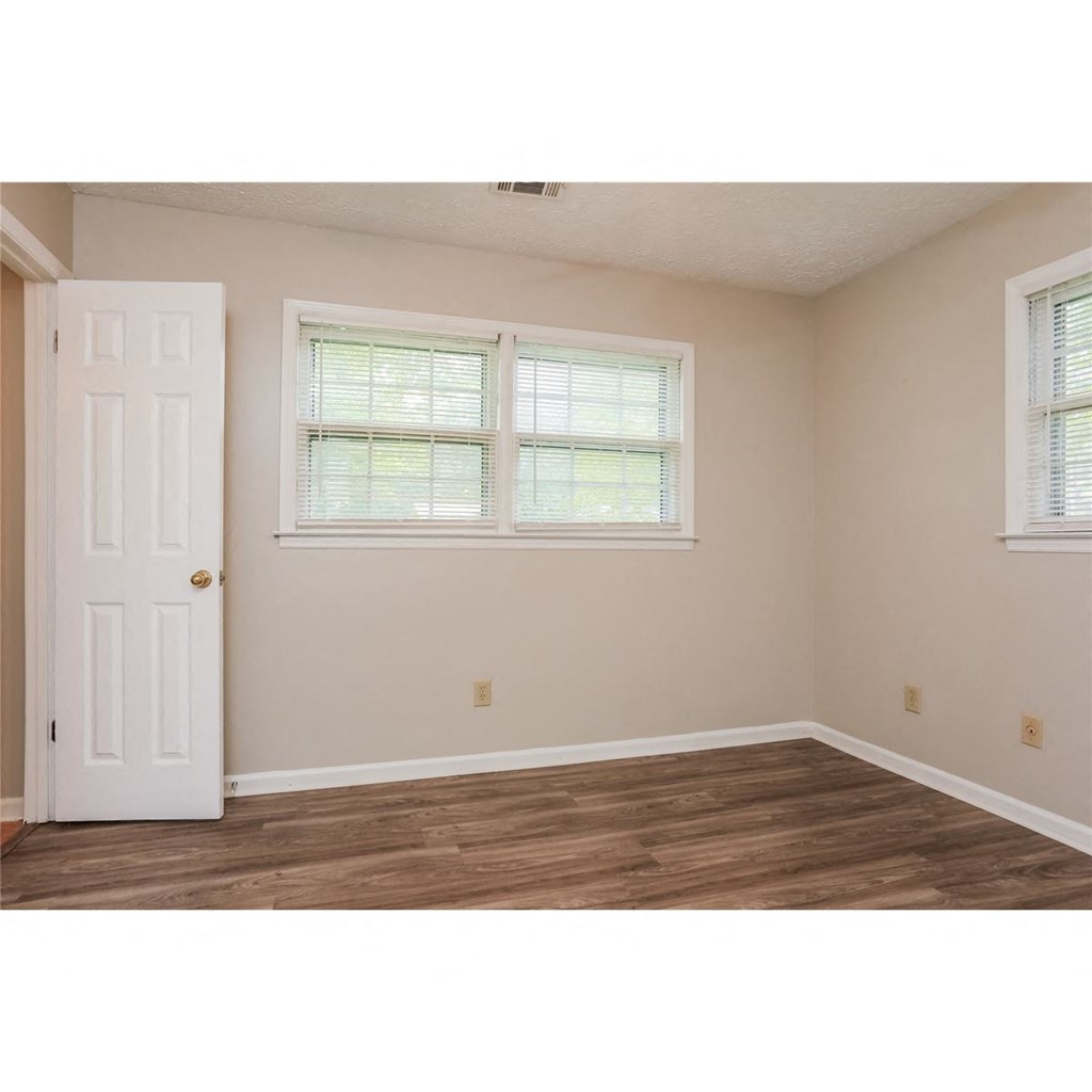 an empty room with a white door and two windows