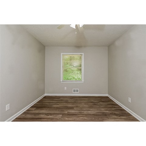 a bedroom with a window and a wood floor