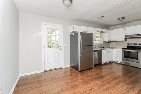 A kitchen with a refrigerator, oven, and microwave.
