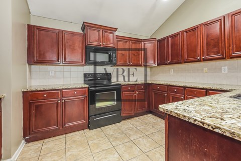 A kitchen with brown cabinets and a black stove top oven.