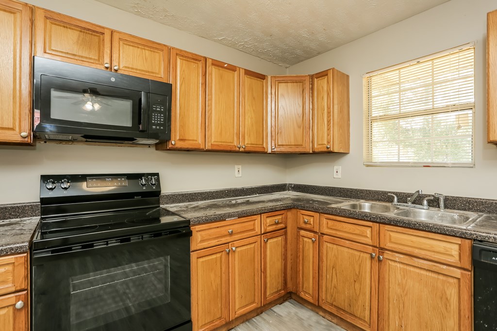 A kitchen with wooden cabinets and black appliances.